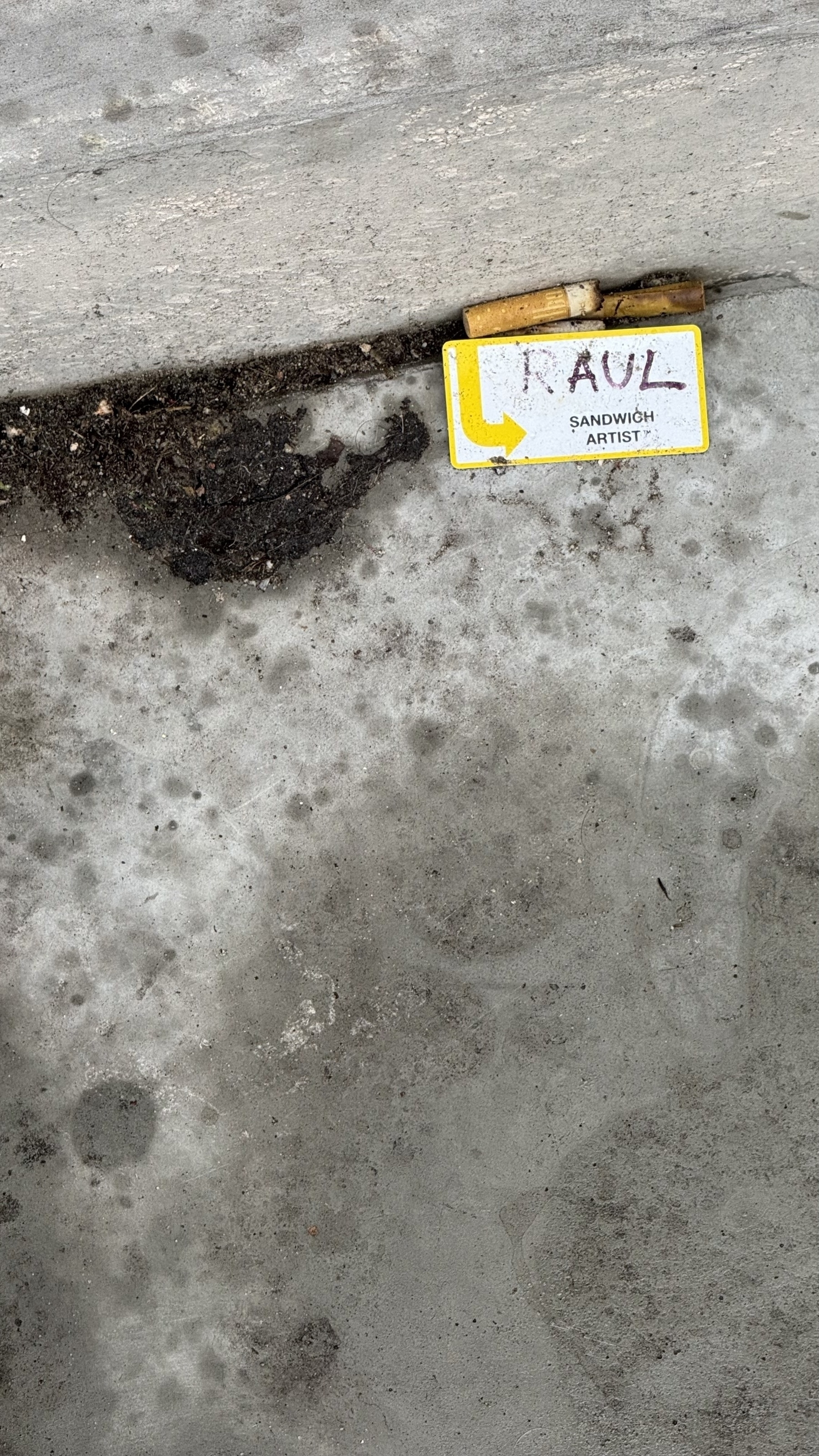 A yellow sign reading "RAUL" is placed on a gray concrete surface.