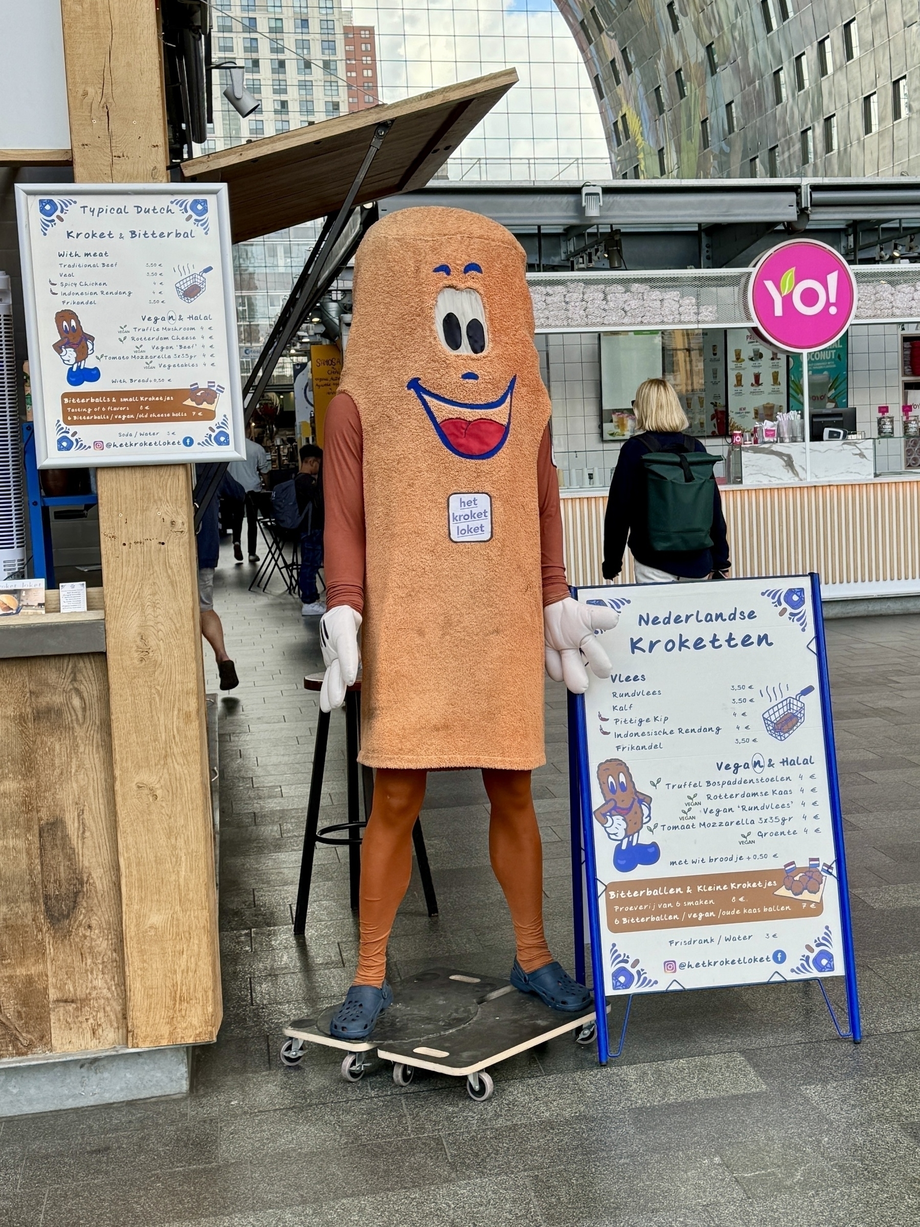 A sign displays “Dutch Vegan & Halal Kroketten” with images of meat and vegetables.