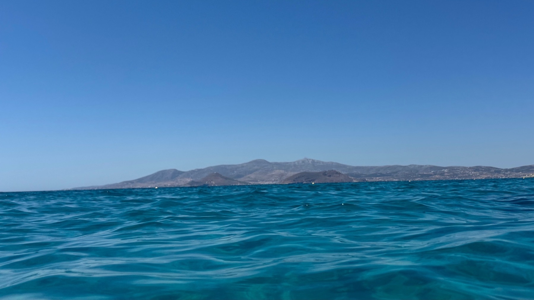 Blue water with ripples and a distant mountain range visible in the background.