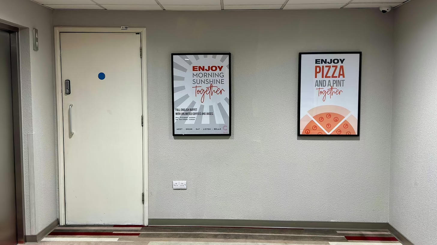 Two framed posters are on a white wall: one reads "ENJOY SUNSHINE TOGETHER" and the other "ENJOY PIZZA AND A PINT TOGETHER.