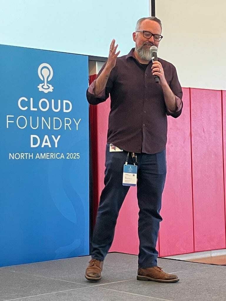 A man speaks at a conference with a "Cloud Foundry Day North America 2025" banner visible in the background.