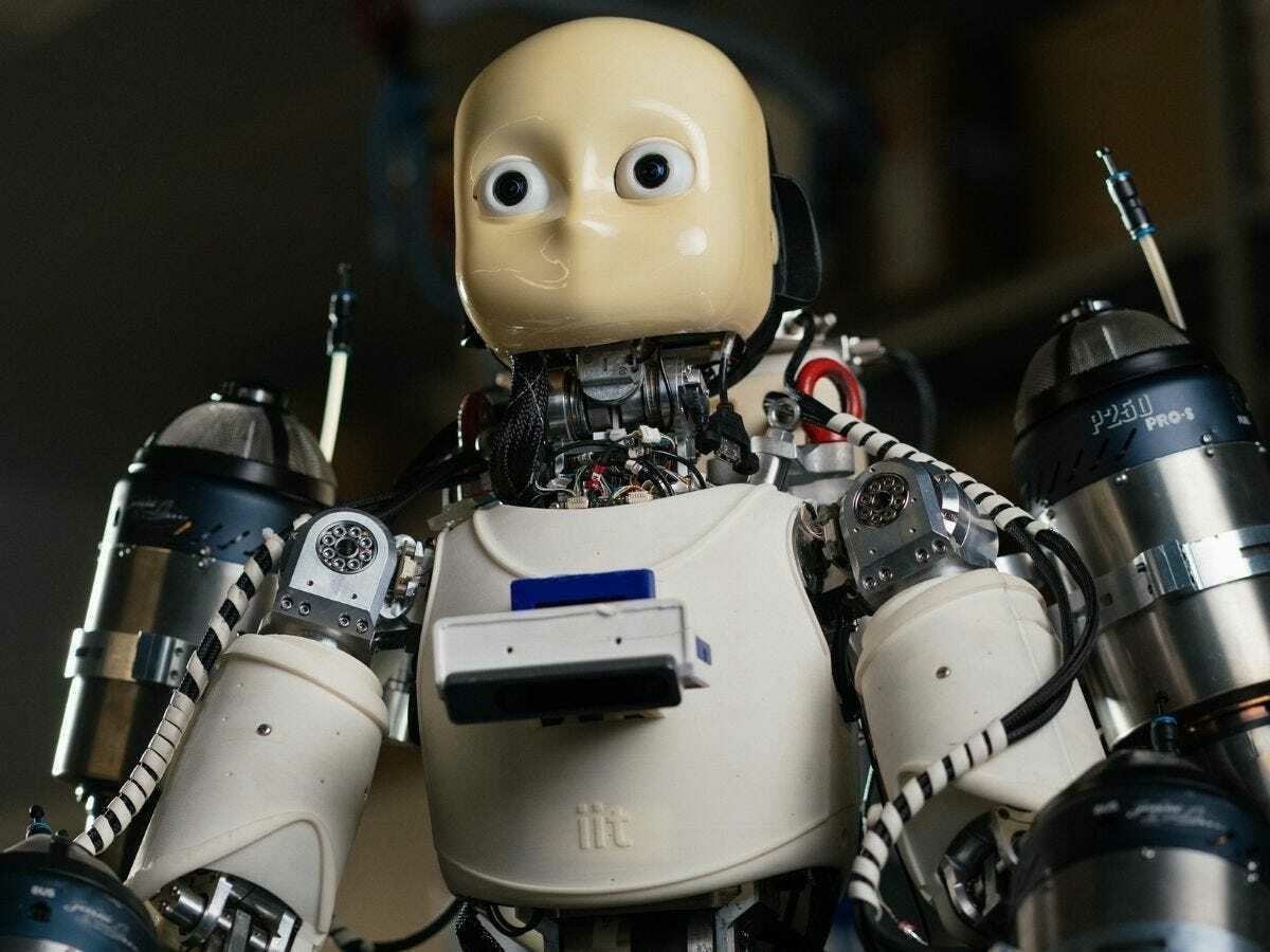 Close-up of a humanoid robot showing intricate mechanical components and wiring with small jet engines on its arms and torso.