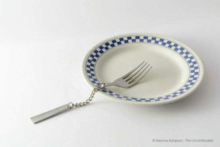 A white plate with blue and white checkered pattern is connected to a silver fork by a chain.