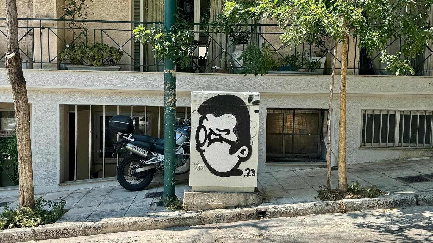 A black and white graffiti portrait of a man with the number 23 is next to a parked motorcycle.