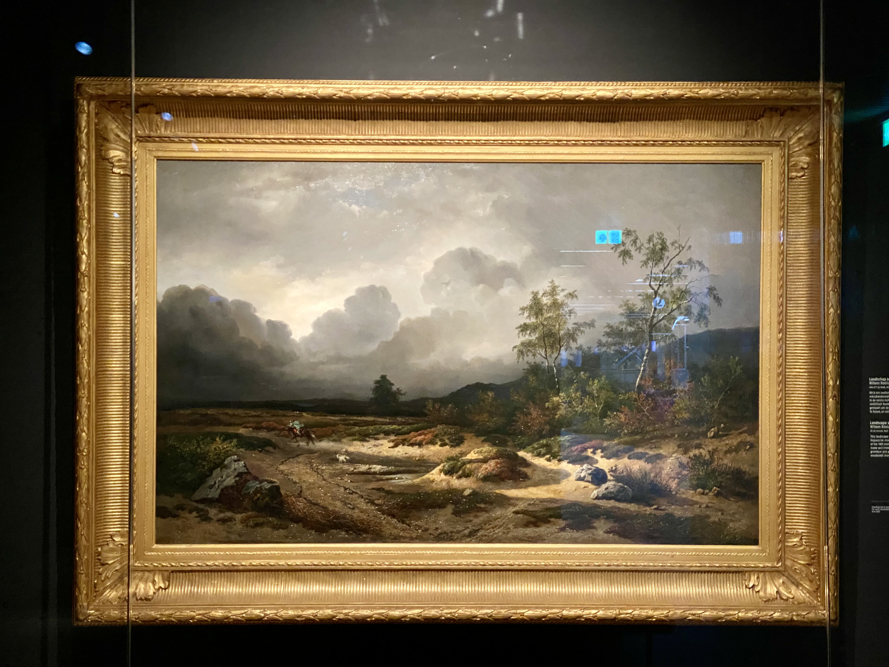 A landscape painting depicts a dark, stormy scene with a path and a lone tree under a cloudy sky.