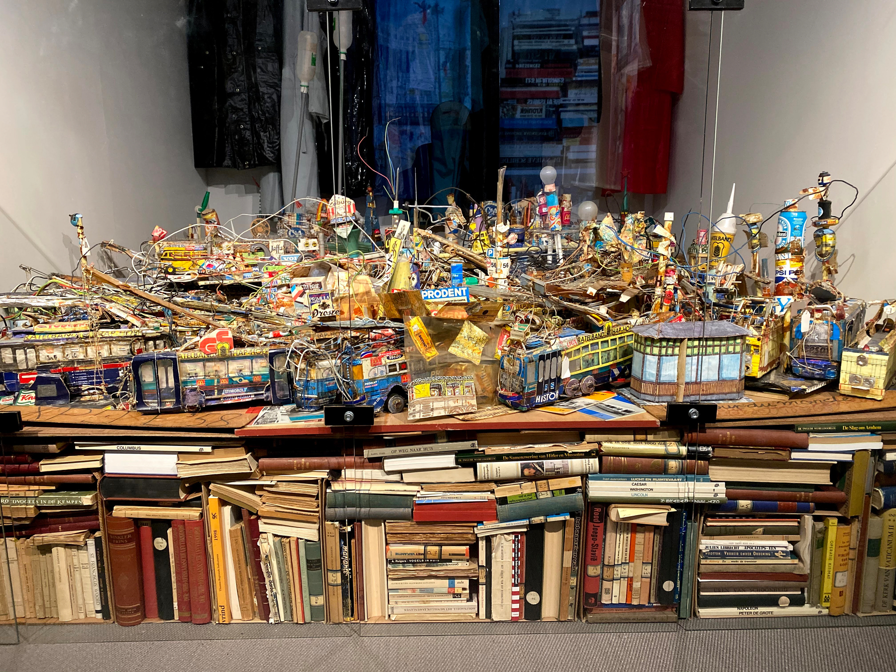 A chaotic display of vintage toys and books, including “Prodent” and “Peter Pan” titles, is stacked against a white wall.