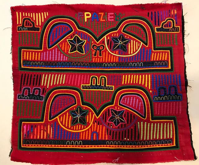 Red textile with stylized animal faces and geometric patterns.