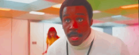 Man with an expression of shock and surprise, a person visible in the background