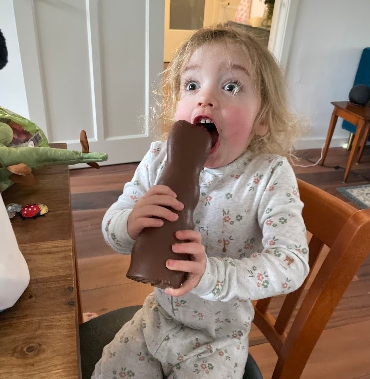 Child excitedly holds a chocolate bunny, mouth wide with anticipation