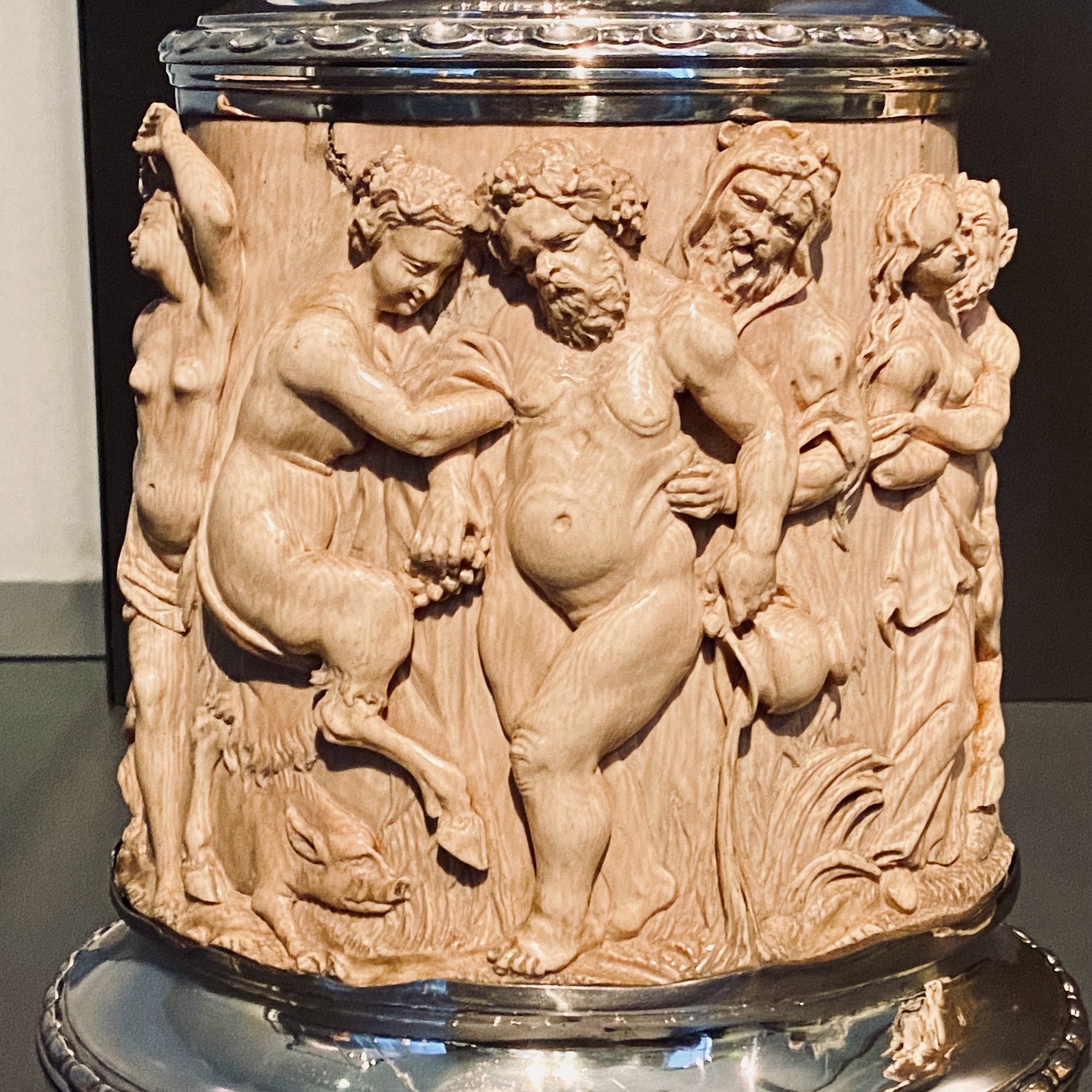 Carved ivory tankard mounted in silver, its body a high-relief bacchanal: a pot-bellied Silenus staggering at the centre, flanked by satyrs, a maenad with a bunch of grapes, and a boar at his feet.