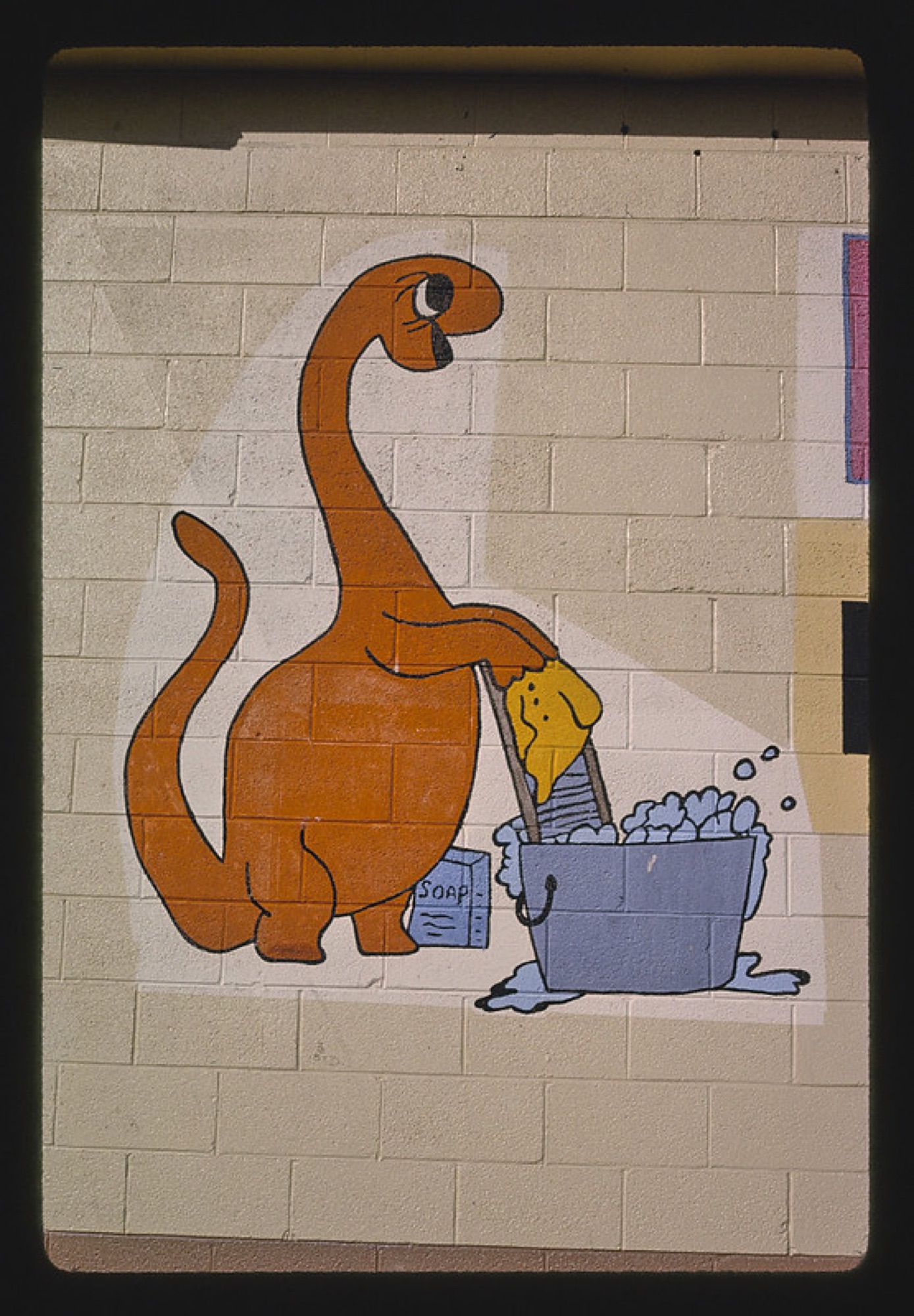 Detail of a laundromat facade sign in Utah featuring a painted dinosaur